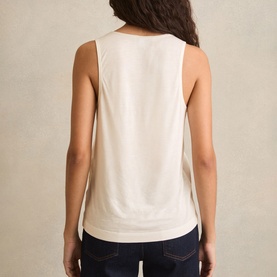 Model wearing Reiss white sleeveless top, back view, styled with dark navy jeans