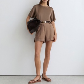 Model wearing Reiss taupe brown shorts and matching T-shirt, styled with a brown leather belt, dark bag and tan flat sandals.