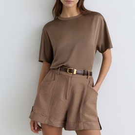 Model wearing Reiss taupe brown co-ord set with short-sleeve top and tailored shorts, styled with a brown leather belt with gold buckle.