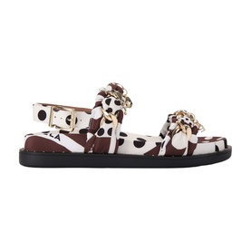 Brown and white cow-print flat sandals with gold chain embellishment, buckle ankle strap, and black rubber sole