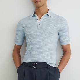 Model wearing Reiss soft blue textured knit polo shirt, styled with navy tailored trousers and belt