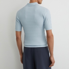 Model wearing Reiss soft blue textured knit polo shirt, short sleeves, rear view, styled with navy shorts.