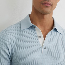 Model wearing Reiss soft blue textured knit polo shirt, close-up detail of ribbed pattern and button placket