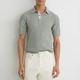 Model wearing Reiss soft sage textured knit polo shirt with short sleeves, styled with cream trousers