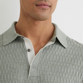 Model wearing Reiss soft sage ribbed polo shirt, close-up showing contrast white placket and snap button collar detail