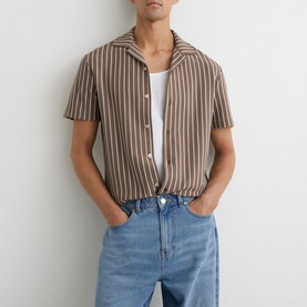 Model wearing Reiss brown vertical stripe short-sleeve camp collar shirt, styled with white tee and light blue jeans