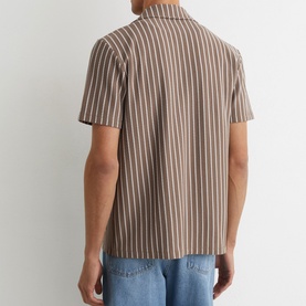 Model wearing Reiss brown vertical stripe short-sleeve shirt, back view, styled with light blue jeans.
