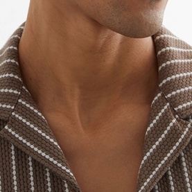 Model wearing Reiss brown striped shirt, close-up detail of collar and textured fabric with white stripe pattern