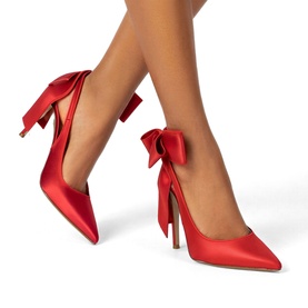 Model wearing Steve Madden red satin pointed-toe stiletto heels with oversized bow detail at the ankle