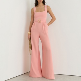 Model wearing Reiss pink wide-leg jumpsuit with square neckline, belt detail, and broad straps, styled with a woven clutch bag.