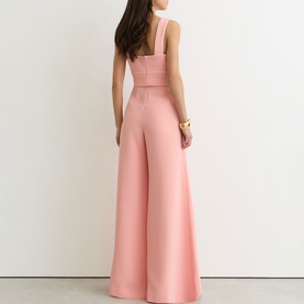 Model wearing Reiss pink wide-leg jumpsuit with square neckline and fitted bodice, shown from back, styled with gold bracelet