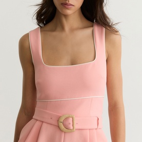 Model wearing Reiss pink dress with white piping trim and rattan buckle belt detail, square neckline, sleeveless style.