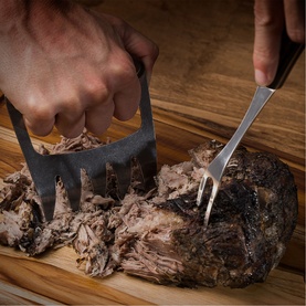 Tramontina stainless steel carver claws and fork shredding slow-cooked pulled pork on a wooden board