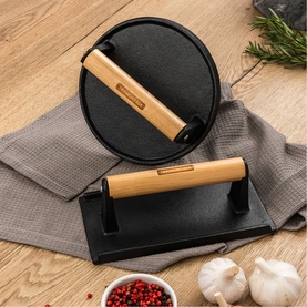 Tramontina black cast iron press set with bamboo handles, styled on wooden surface with garlic and herbs