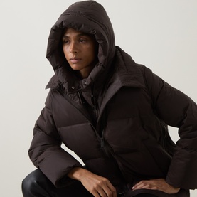 Model with Yves Salomon Padded Hood Bib in Cold Brew, sleeveless quilted down-filled bib with adjustable hood, styled over dark jacket