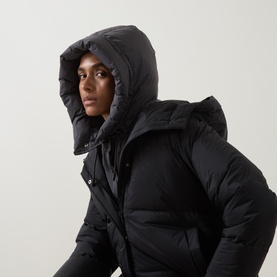 Model wearing Yves Salomon Padded Hood Bib in grey, sleeveless quilted down-filled design with adjustable drawstring hood, styled over black jacket