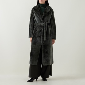 Model wearing Yves Salomon Long Belted Shearling Coat in grey, notched lapel, self-tie belt, long silhouette. Styled with wide-leg trousers