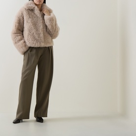 Model wearing Yves Salomon beige shearling cropped coat with khaki wide-leg trousers and black heeled loafers.