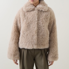 Model wearing Yves Salomon beige shearling cropped coat with wide collar, styled with khaki trousers.