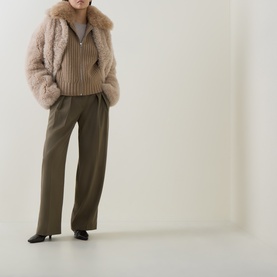 Model wearing Yves Salomon beige shearling jacket with ribbed knit top, olive wide-leg trousers and black kitten heel shoes.