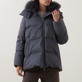 Model wearing Yves Salomon grey padded down jacket with faux fur-trimmed hood, styled with a chunky knit jumper underneath.