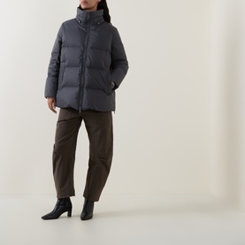 Model wearing Yves Salomon grey hooded puffer jacket, styled with brown trousers and black heeled boots