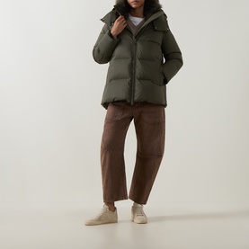 Model wearing Yves Salomon herbal tea puffer jacket with hood, styled with brown wide-leg trousers and beige trainers.