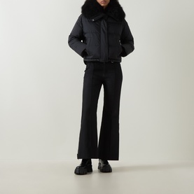 Model wearing Yves Salomon Cropped Down Jacket in black with removable shearling collar, styled with wide-leg black trousers and chunky loafers