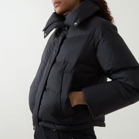 Model wearing Yves Salomon Cropped Down Jacket in black, showing puffer silhouette, high collar, and hands-in-pocket styling