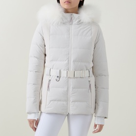 Model wearing Yves Salomon Fur-Trim Padded Ski Jacket in Mont Blanc with fur-trimmed hood and matching buckle belt, styled with white trousers