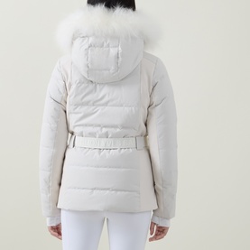 Model wearing Yves Salomon Fur-Trim Padded Ski Jacket in Mont Blanc, rear view, white fur-trimmed hood, belted waist, styled with white ski trousers.