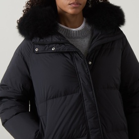 Model wearing Yves Salomon black puffer jacket with oversized black fur-trimmed hood, styled with a grey knit jumper.