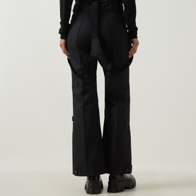 Model wearing Yves Salomon Salopettes Flared-Leg Ski Trousers in black, rear view, showing flared leg and adjustable suspenders.