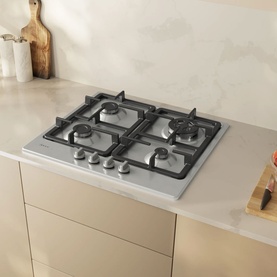 Neff silver 4-burner gas hob with cast iron pan supports, built into a cream kitchen worktop, styled with wooden accessories.