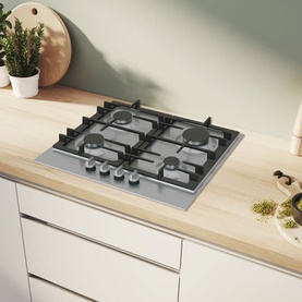 Bosch silver 4-burner gas hob set into a light wood kitchen worktop, shown in a styled kitchen setting with white cabinetry
