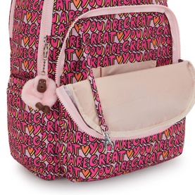 Kipling backpack in U R Great Prt print, open front pocket detail showing pink interior lining and signature monkey keychain.