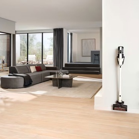Miele Triflex HX3 white cordless stick vacuum cleaner docked on wall mount in bright modern living room
