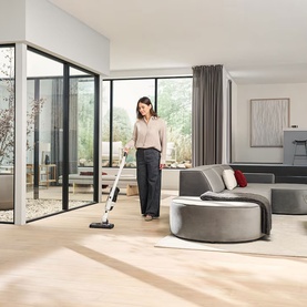 Miele Triflex HX3 white cordless vacuum cleaner in use on light wood floor in bright modern living room