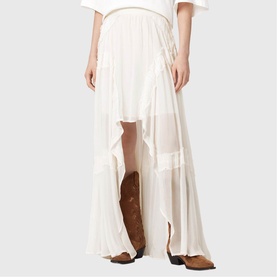 Model wearing All Saints Dorina Asymmetric Skirt in antique white with high-low hemline and gathered panels, styled with brown cowboy boots.