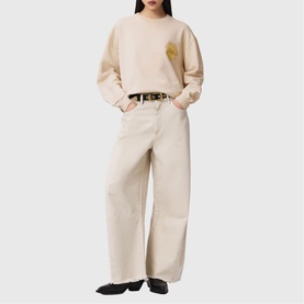 Model wearing All Saints Sun City Etta Sweatshirt in Birch White with sun city artwork, styled with matching wide-leg trousers and belt.
