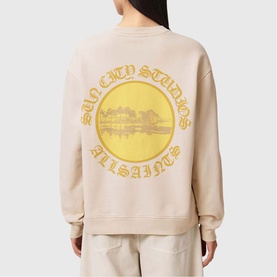 Model wearing All Saints Sun City Etta Sweatshirt in Birch White with yellow sun city graphic print on back, styled with cream wide-leg trousers.