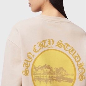 Model wearing All Saints Sun City Etta Sweatshirt in Birch White, showing gold Sun City Studios graphic print on back.