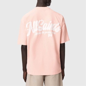 Model wearing All Saints Odyssey Oversized Bubble Logo T-Shirt in Blushed Pink, shown from back with white bubble logo print.