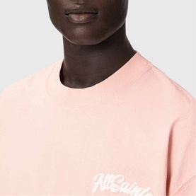 Model wearing All Saints Odyssey Oversized Bubble Logo T-Shirt in Blushed Pink, close-up showing white bubble logo script at chest