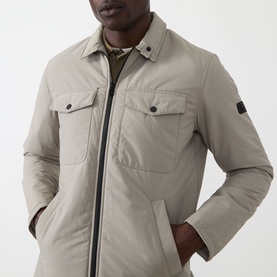 Model wearing Barbour International Casual Jacket in Concrete, zip-through with twin chest pockets and arm badge detail, styled with olive polo shirt.