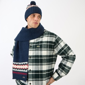 Model wearing Barbour Kane Logo Beanie Hat & Scarf Gift Set in evergreen, fair isle scarf and pom-pom beanie, styled with green plaid overshirt