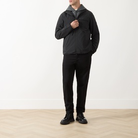 Model wearing Barbour International Dalliston Logo Jacket in black, hooded zip-up style, styled with black trousers and leather shoes.