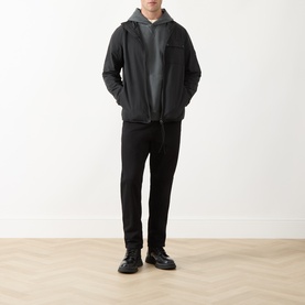 Model wearing Barbour International Dalliston Logo Jacket in black with hood, styled with grey hoodie and black trousers.