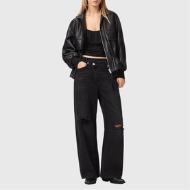 Model wearing All Saints Celena Logo Strap Top in black with lace straps, styled with black leather jacket and wide-leg ripped jeans.