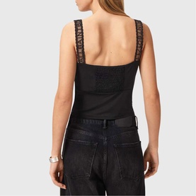 Model wearing All Saints Celena Logo Strap Top in black, showing smocked back panel and logo-embroidered lace straps, styled with dark jeans.